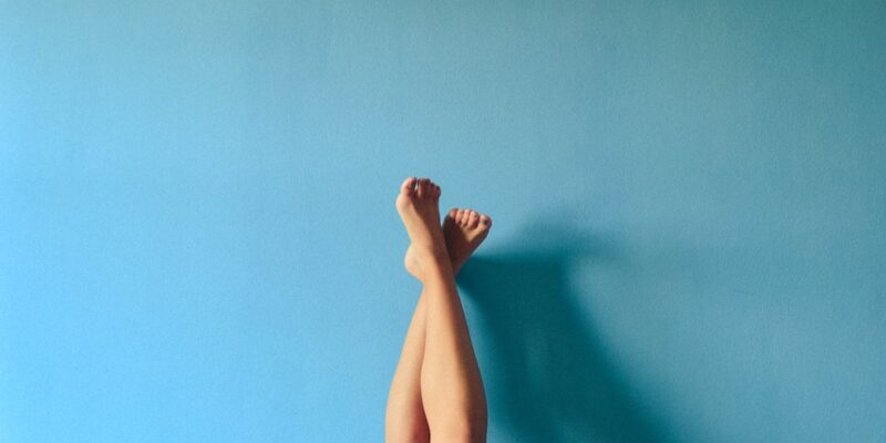 A woman's legs against a blue wall.