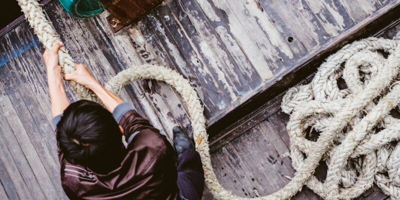 A man is pulling a rope on a boat.