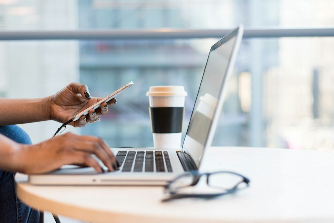 A woman using a laptop and cell phone.