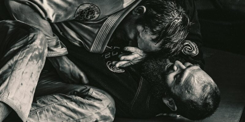 A black and white photo of two men in a jiu jitsu class.