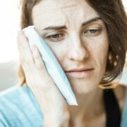 A woman is holding a tissue to her face.