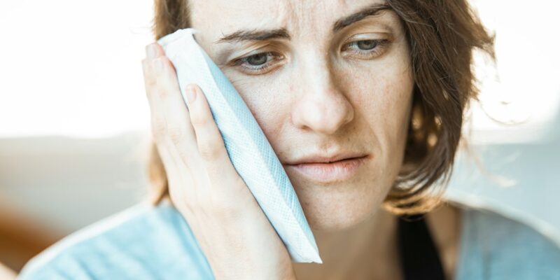 A woman is holding a tissue to her face.