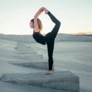 A woman is doing yoga on a concrete slab.