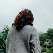 A woman is standing on a hill overlooking a forest.