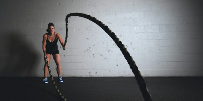 A woman is holding a rope in a gym.