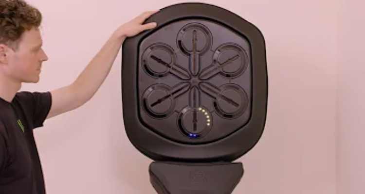 Man demonstrating a wall-mounted directional audio speaker as part of the Liteboxer Fitness Bundle.