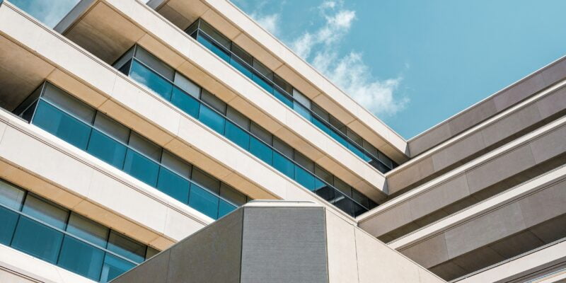 Modern architectural building with geometric design under a blue sky with clouds.