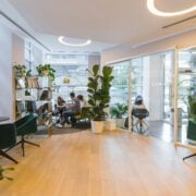 Modern cafe interior with customers, green plants, and stylish furniture.