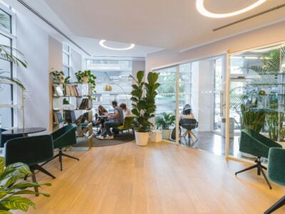 Modern cafe interior with customers, green plants, and stylish furniture.