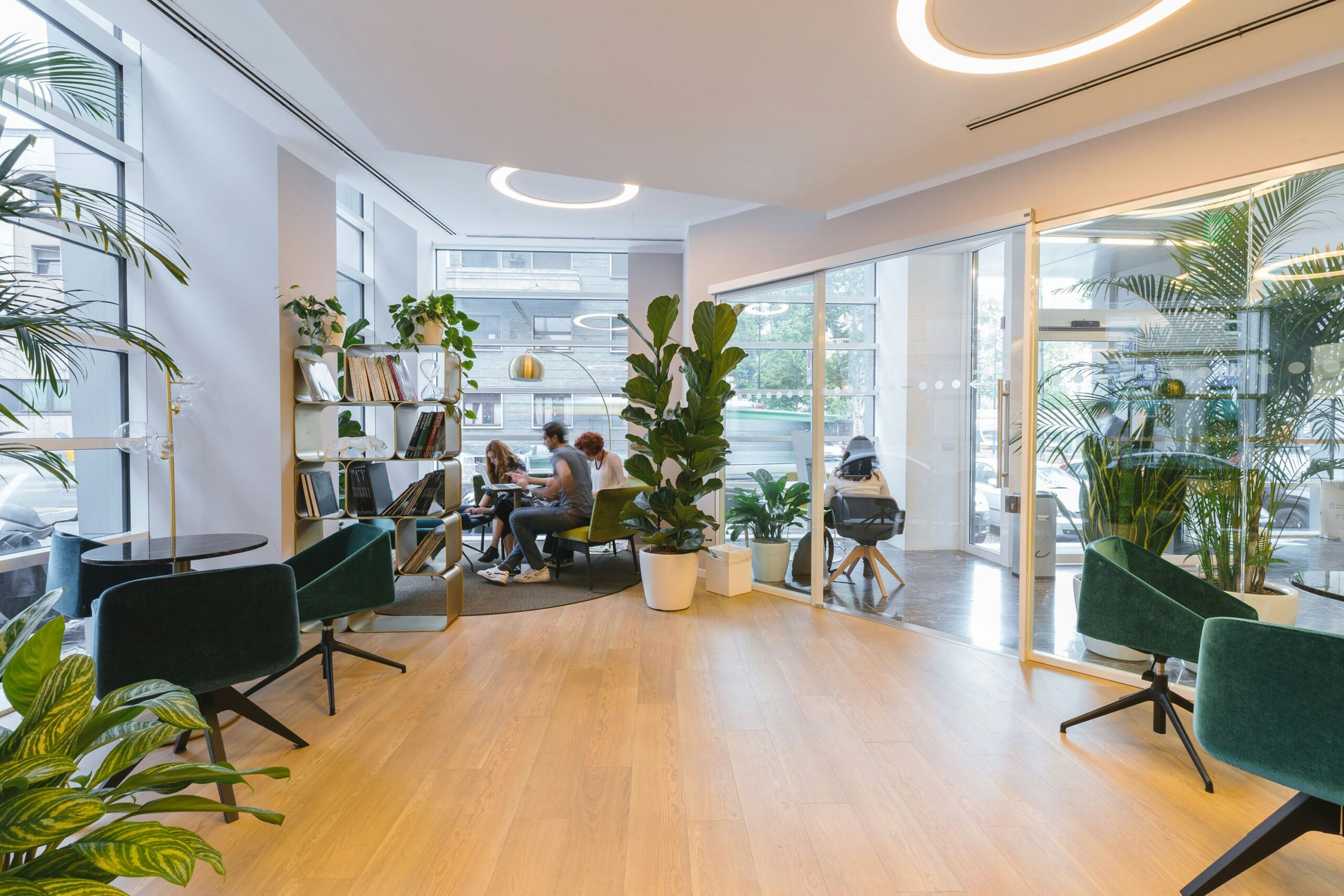 Modern cafe interior with customers, green plants, and stylish furniture.