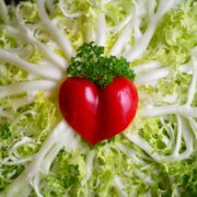 A red heart is shaped out of lettuce.