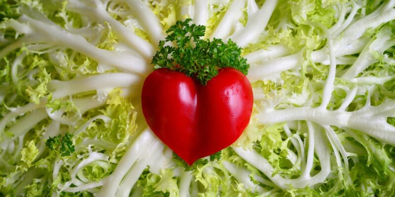 A red heart is shaped out of lettuce.