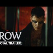 A person with dark eye makeup reflected in a broken mirror, with text overlay indicating "the crow official trailer: a tale of love and redemption.