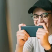 Person playing a game on a smartphone, smiling and focused.