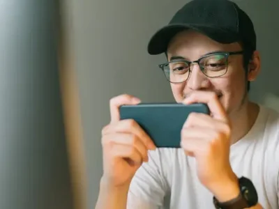 Person playing a game on a smartphone, smiling and focused.