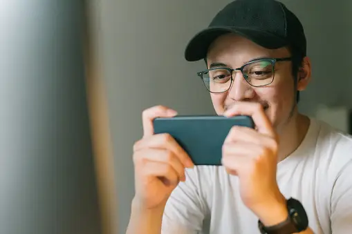 Person playing a game on a smartphone, smiling and focused.