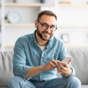 A man sitting on a couch and using a smart phone.