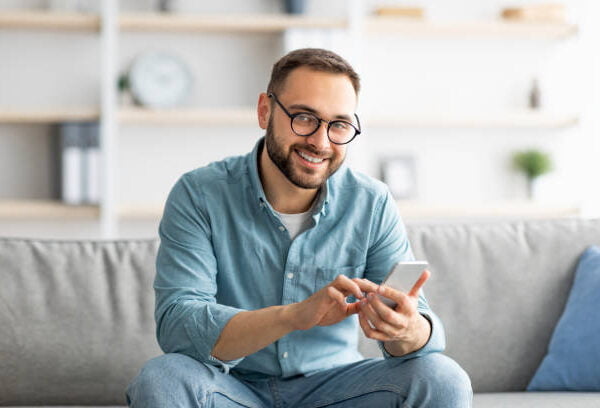 A man sitting on a couch and using a smart phone.