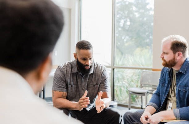 A group of men sitting around a table talking.