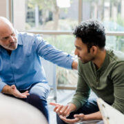 Two men sitting in a room talking to each other.