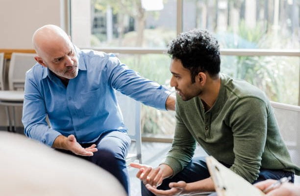 Two men sitting in a room talking to each other.