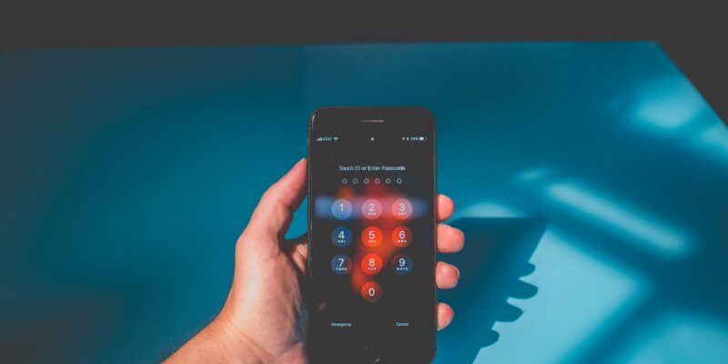 Hand holding a smartphone with a passcode entry screen on display.