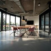 Modern conference room with a long wooden table, contemporary chairs, and large windows providing ample natural light.