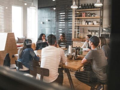 A group of people having a meeting in a modern kitchen setting.