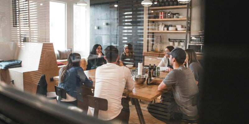 A group of people having a meeting in a modern kitchen setting.