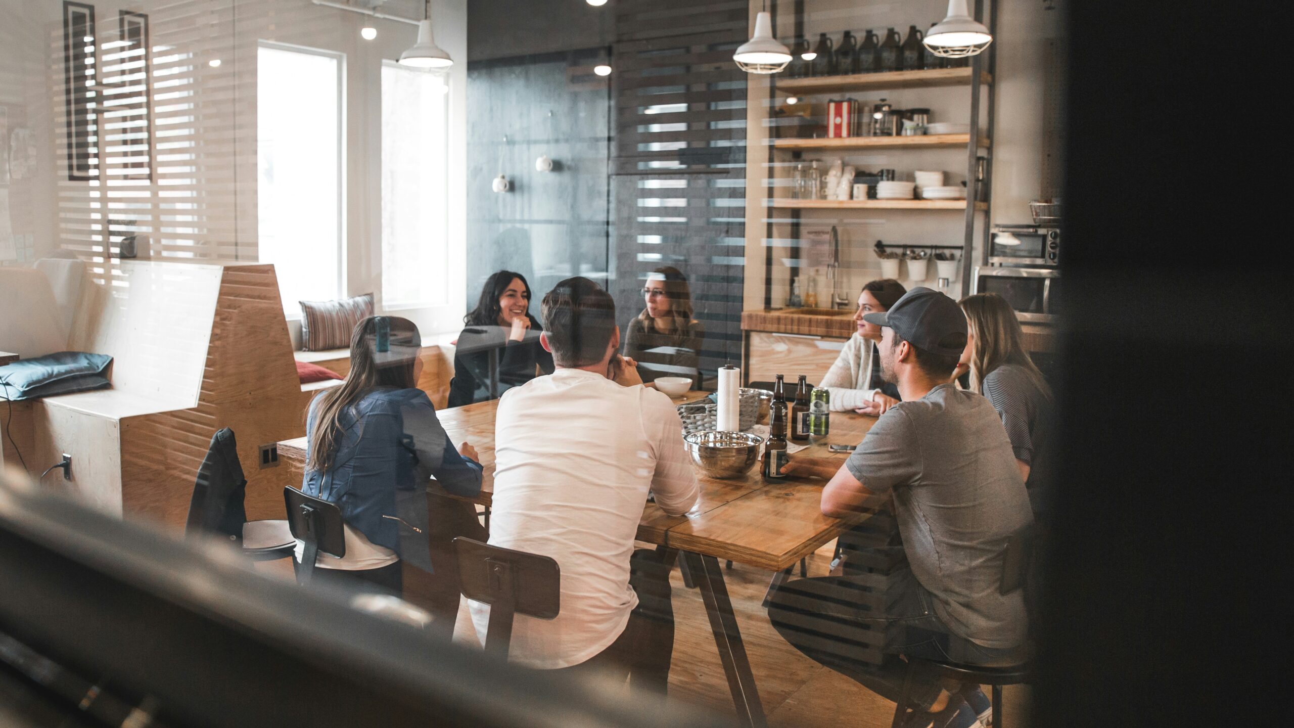 A group of people having a meeting in a modern kitchen setting.