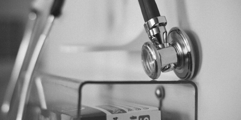 A black and white photo of a stethoscope hanging on a wall.