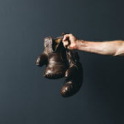 A man holding a pair of boxing gloves on a dark background.