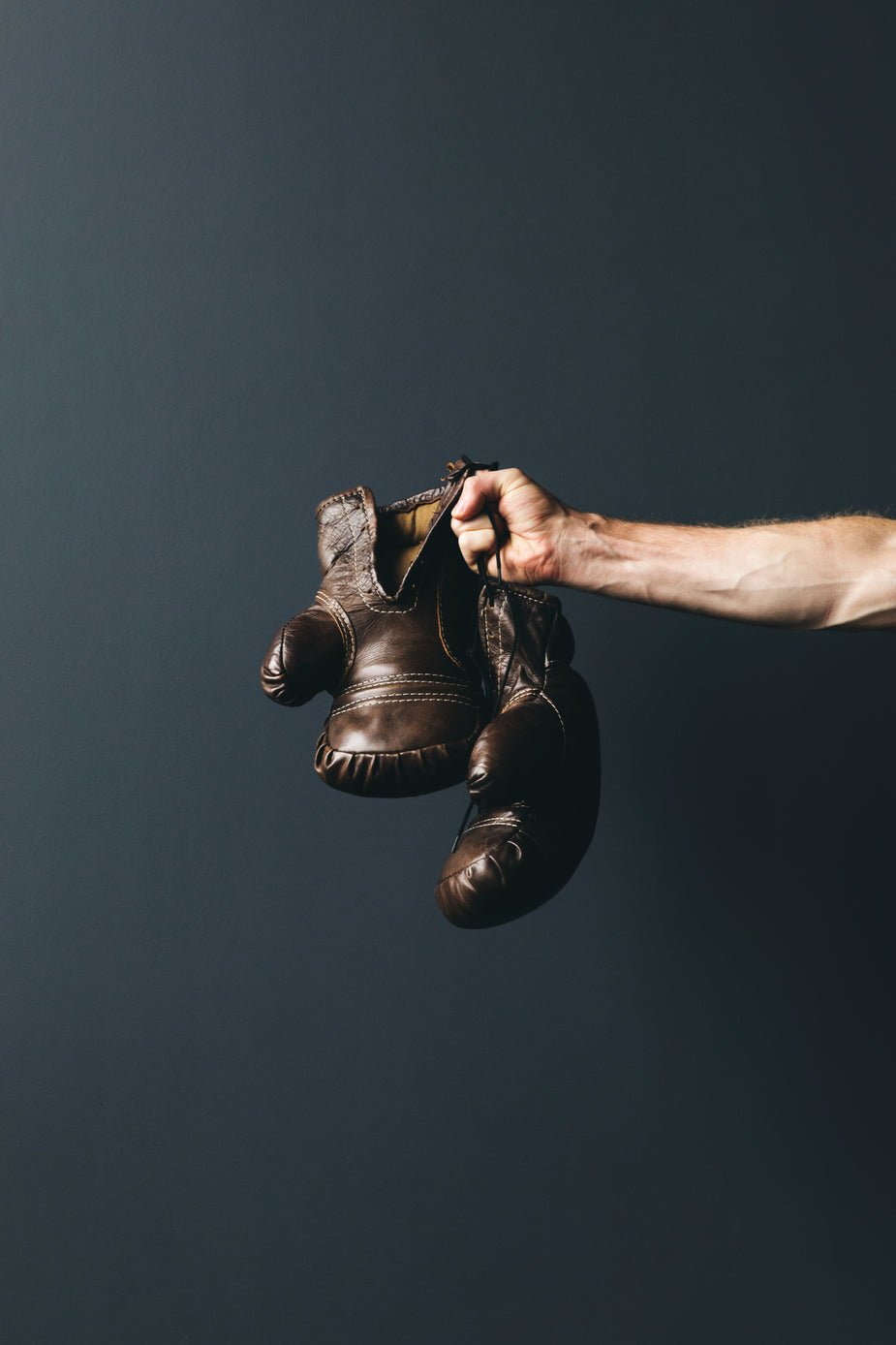 A man holding a pair of boxing gloves on a dark background.