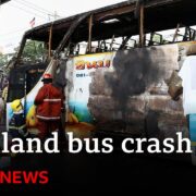 Firefighters and rescue workers surround a severely burnt bus in Thailand after a crash.